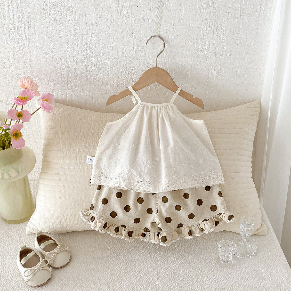 A set of an apricot-colored doll-style blouse and polka-dot shorts for little girls