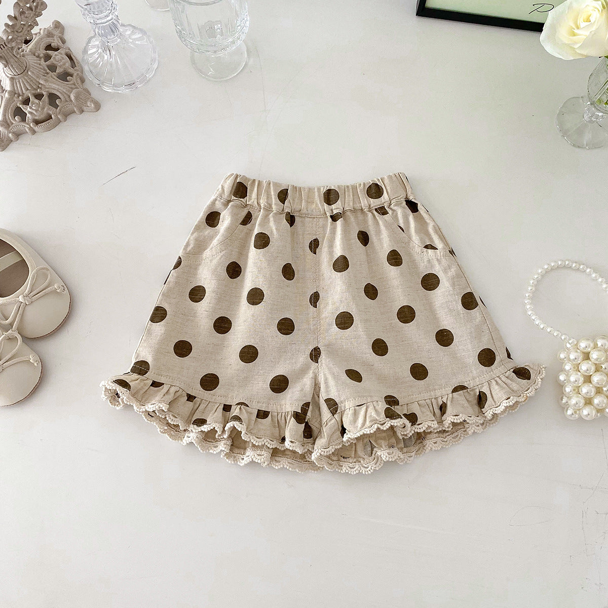 A set of an apricot-colored doll-style blouse and polka-dot shorts for little girls