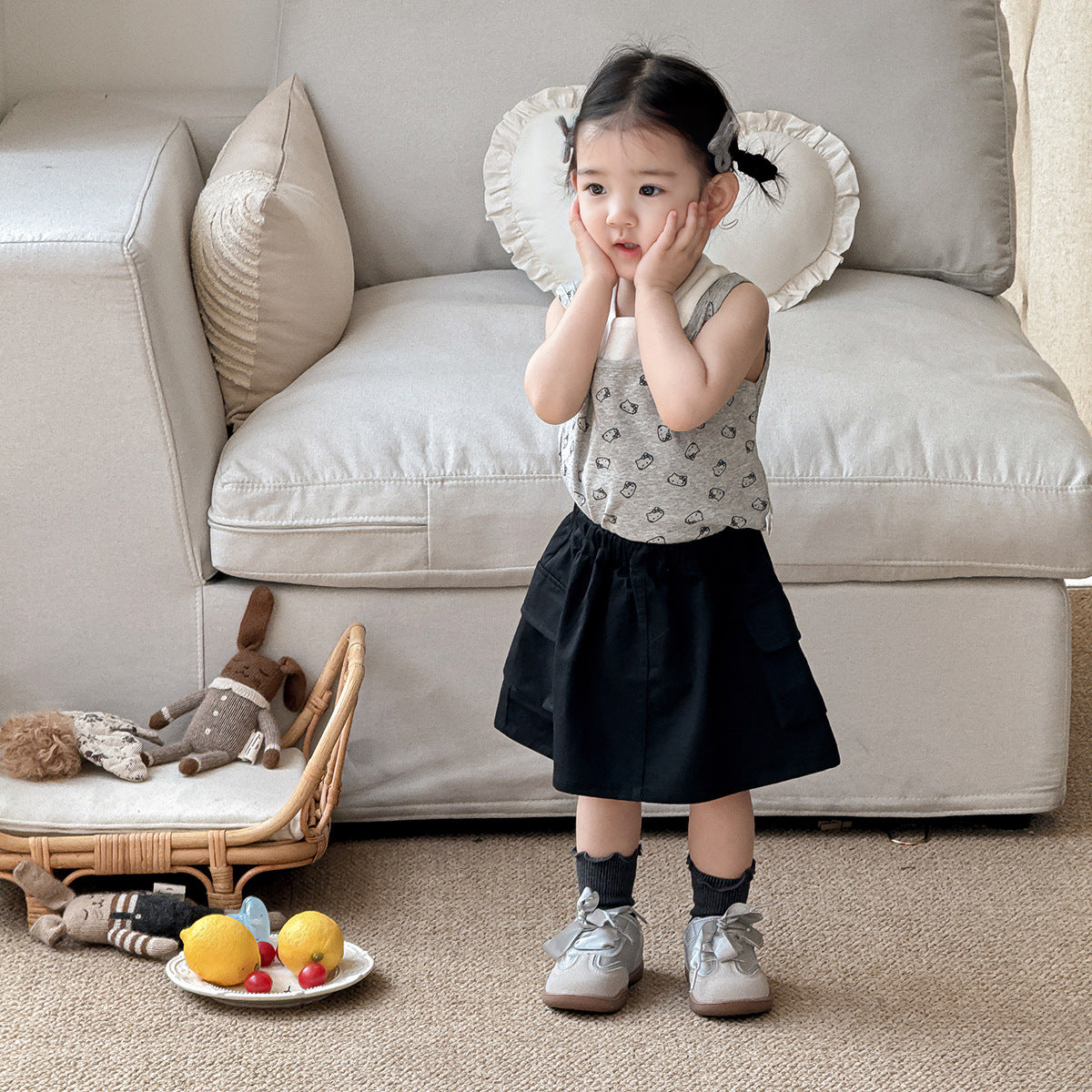 A set of a gray Kitty-themed vest and a black utility-style short skirt for little girls