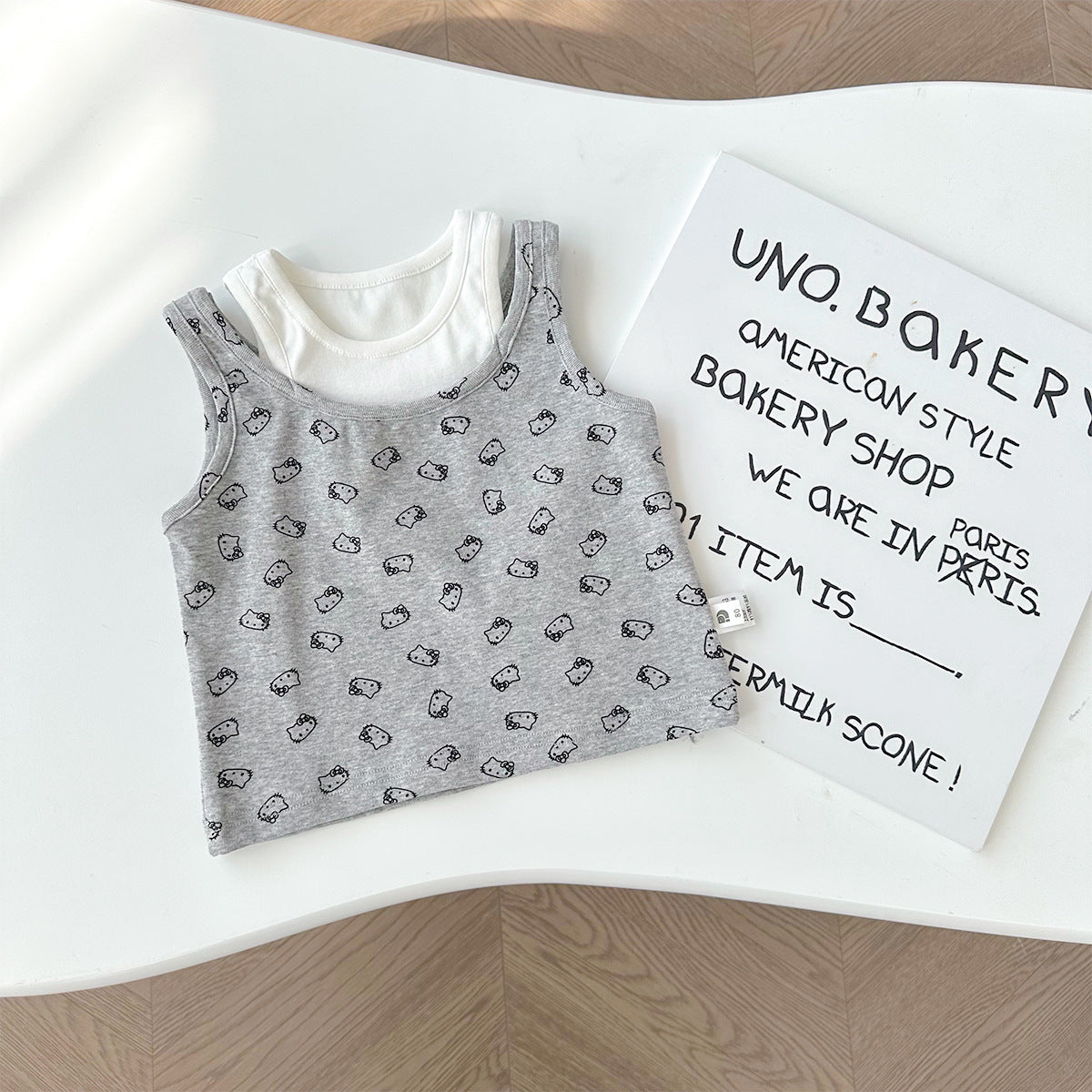 A set of a gray Kitty-themed vest and a black utility-style short skirt for little girls