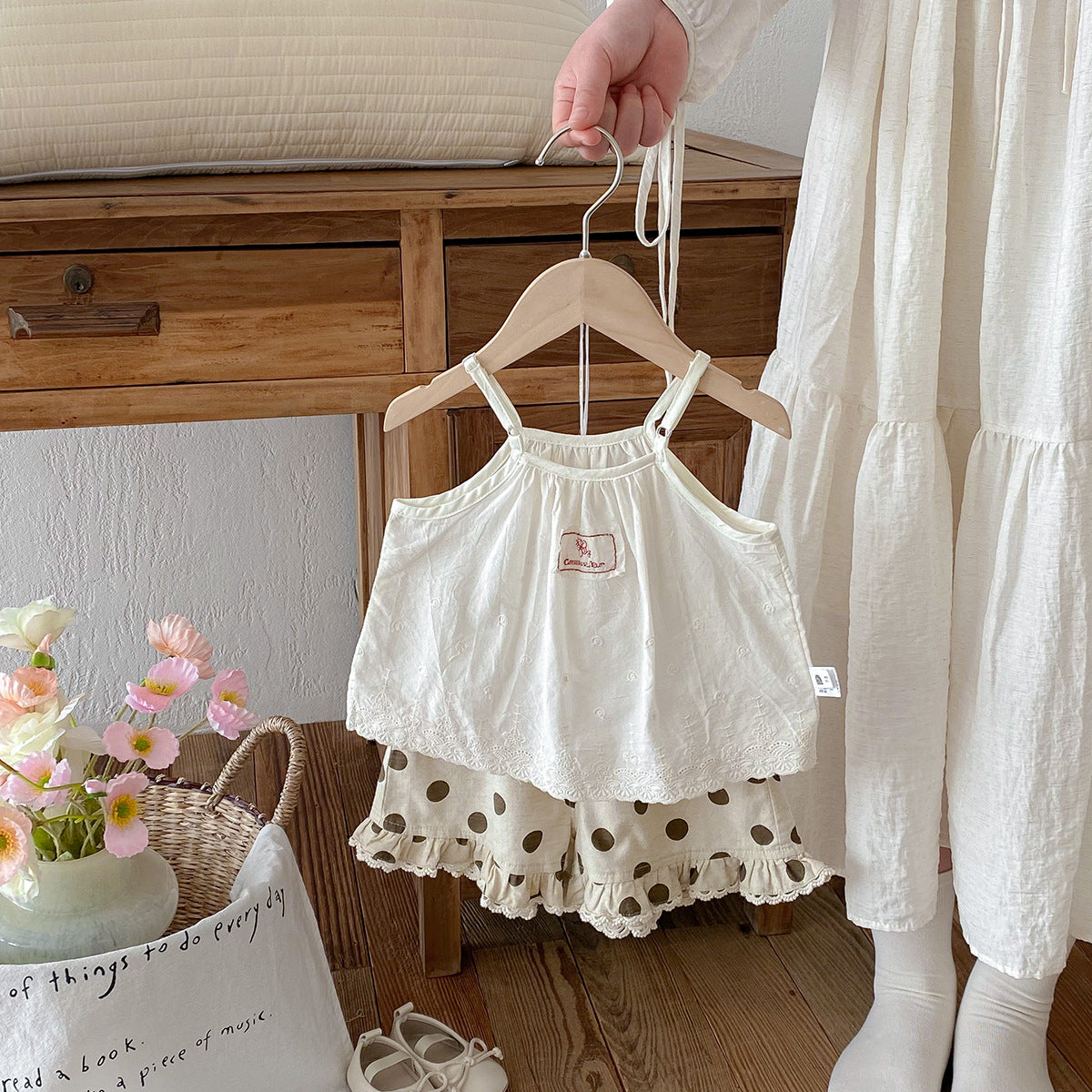 A set of an apricot-colored doll-style blouse and polka-dot shorts for little girls
