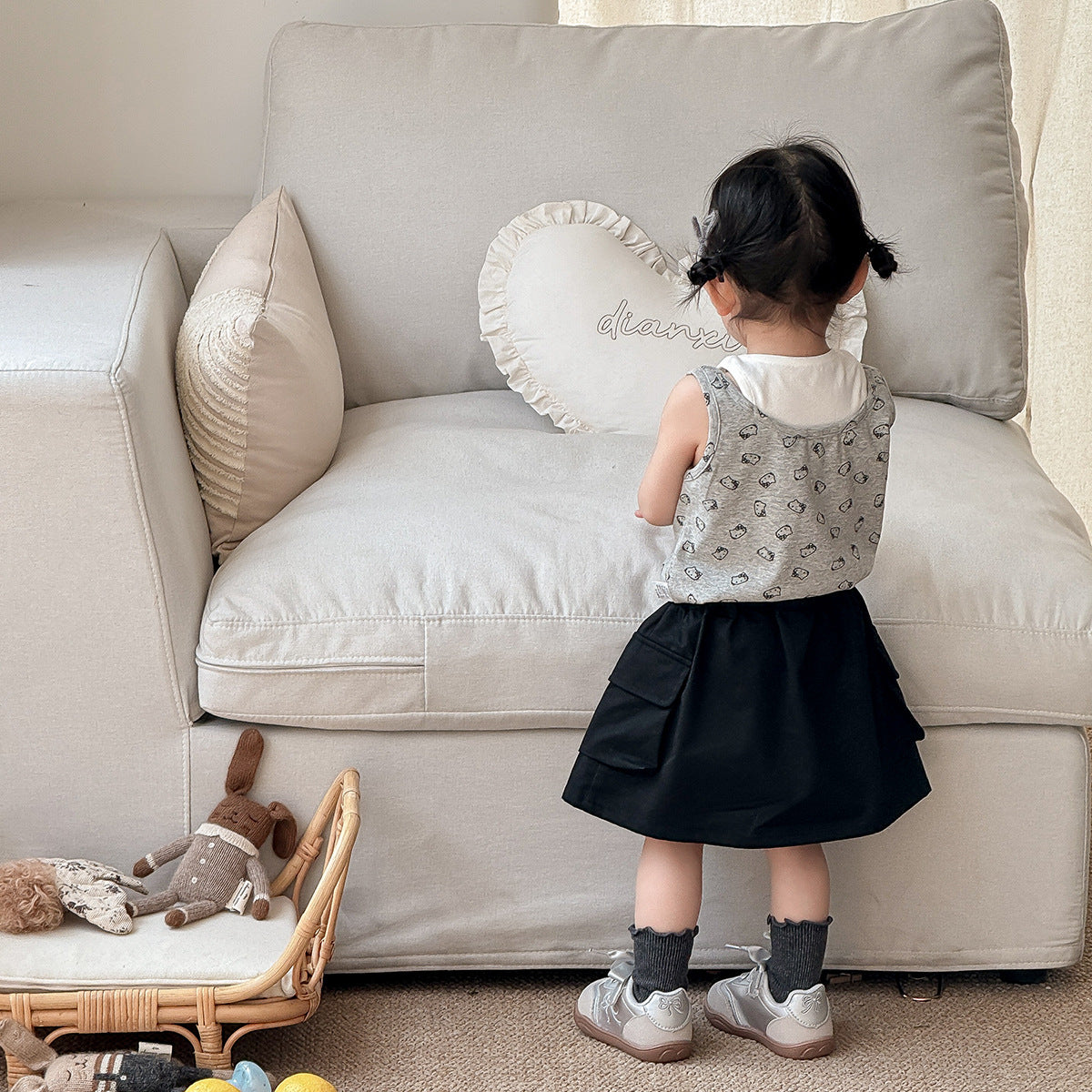 A set of a gray Kitty-themed vest and a black utility-style short skirt for little girls