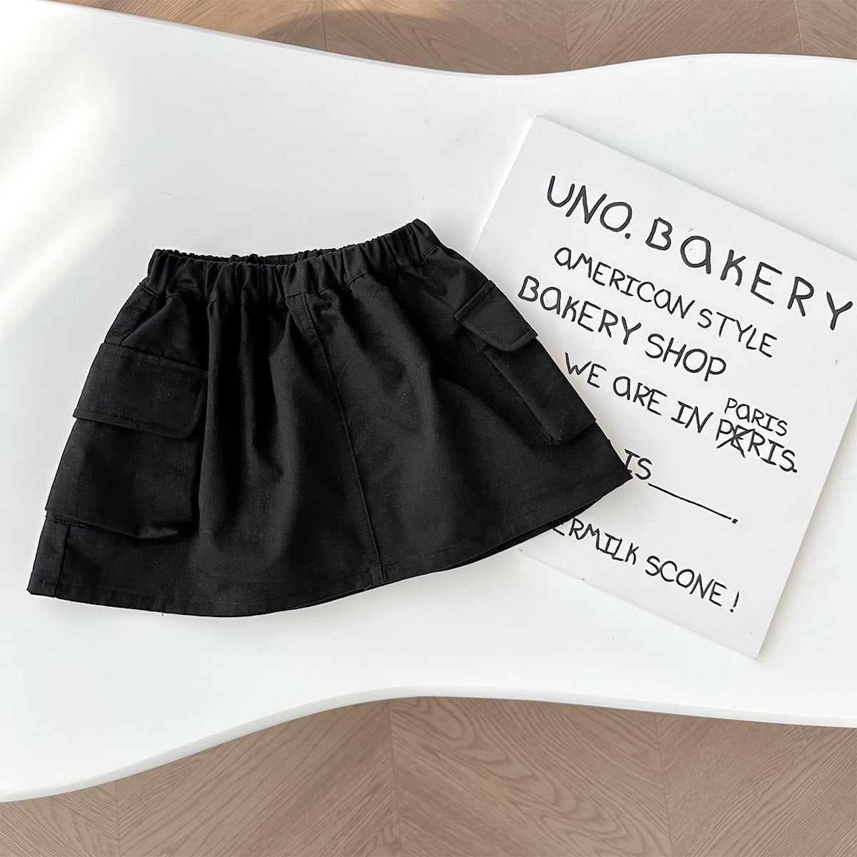 A set of a gray Kitty-themed vest and a black utility-style short skirt for little girls